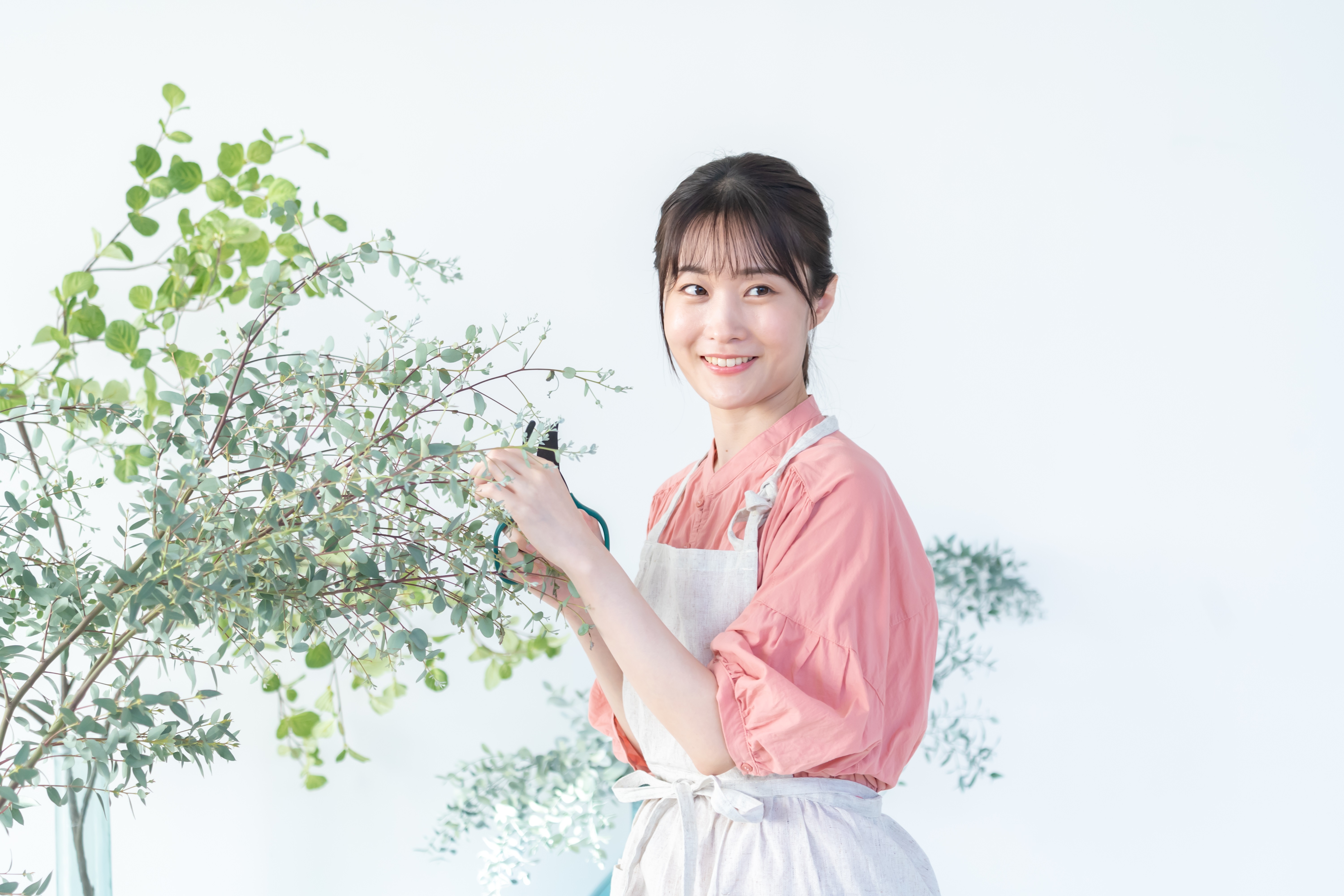 エプロン姿で花の手入れをする女性